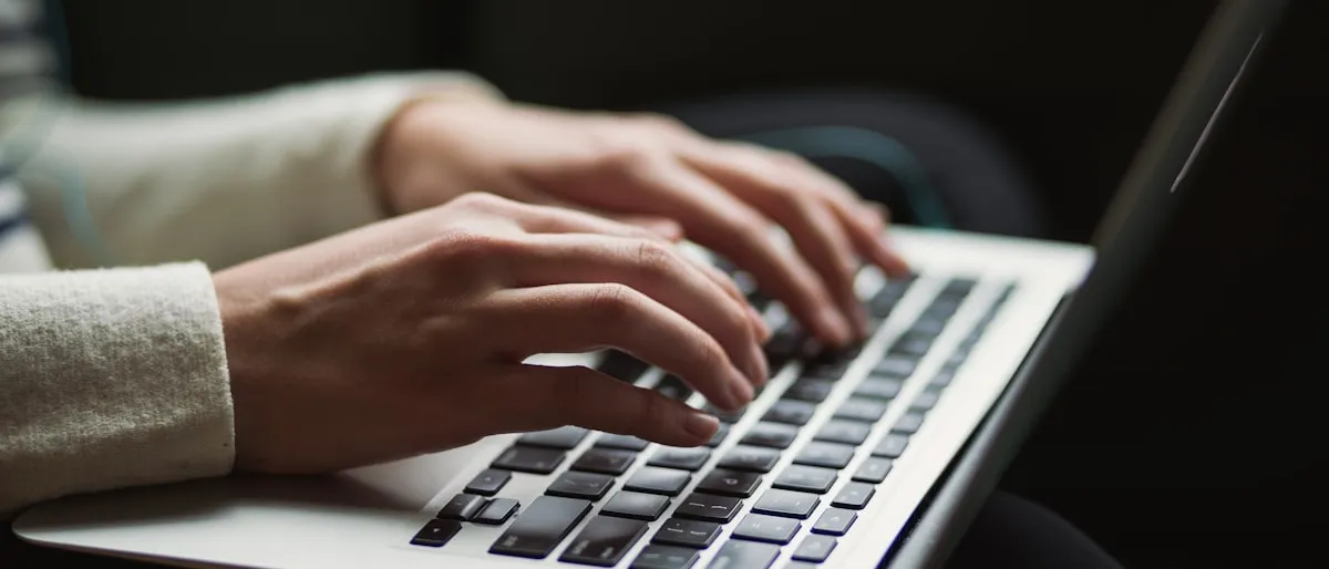 Close-up of hands typing on a laptop keyboard in a dimly lit room