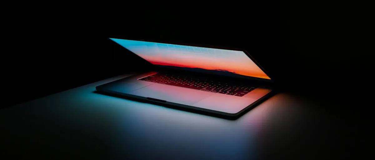 A laptop screen glowing in a dark room, partially open