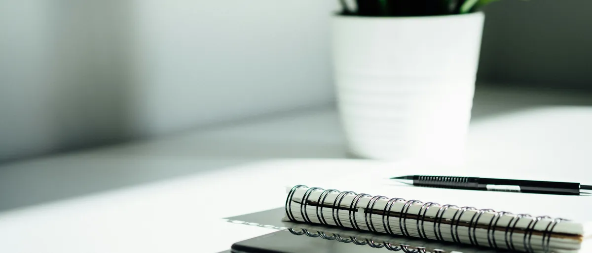 A bank statement and pen resting on a desk next to a keyboard