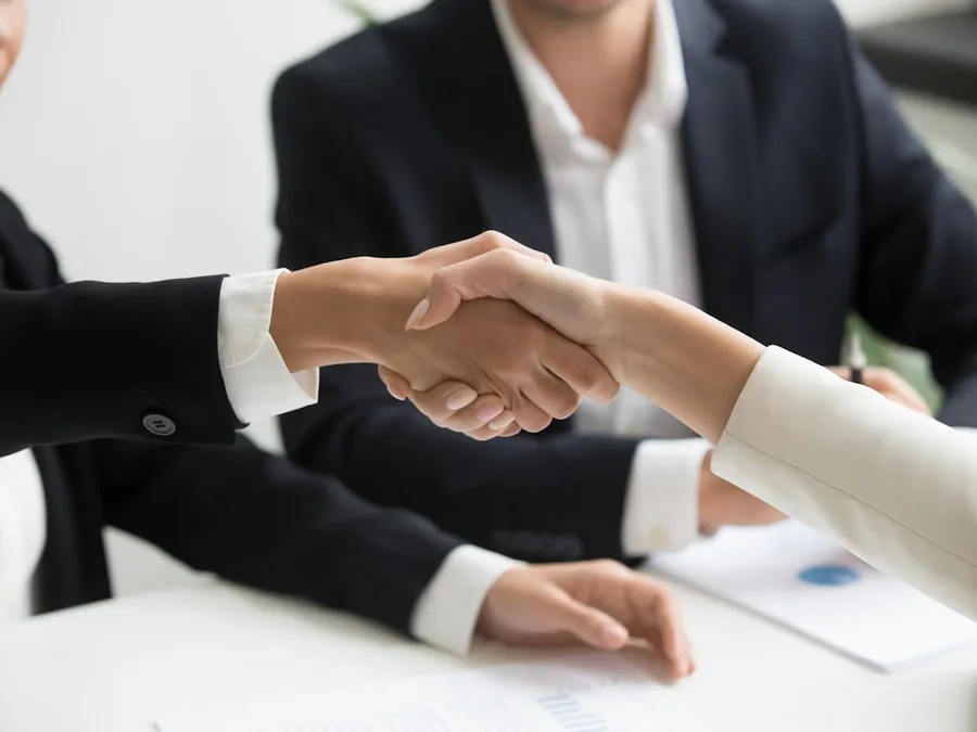 Two professionals shaking hands over a business agreement